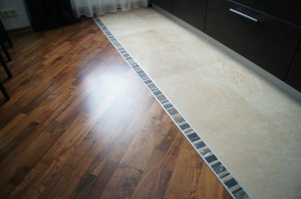 Combined flooring in the kitchen near the work area is laid durable and water-resistant tiles.